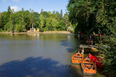 Vista de un lago con botes y bosque en Village Huttopia Senonches, un parque vacacional en Centre-Val de Loire, Francia.