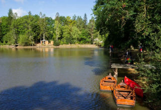 View of a lake with rowboats and forest at Village Huttopia Senonches, a holiday park in Centre-Val de Loire, France.