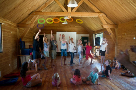 Kinderen en volwassenen spelen met gekleurde ringen in een houten hut bij Village Huttopia Senonches, Frankrijk.