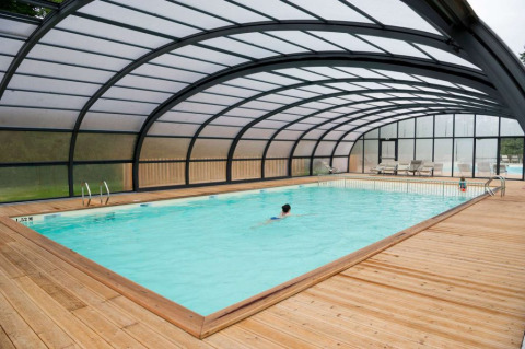 Opvarmet overdækket swimmingpool med træterrasse på Village Huttopia Senonches i Centre-Val de Loire, Frankrig.