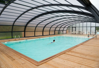 Piscina climatizada cubierta con terraza de madera en Village Huttopia Senonches en Centre-Val de Loire, Francia.