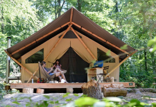 Twee personen ontspannen voor een safaritent in Village Huttopia Senonches, Centre-Val de Loire, Frankrijk.