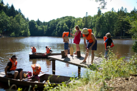 Familias en Village Huttopia Senonches, Francia, navegan en canoa en el lago con chalecos salvavidas.