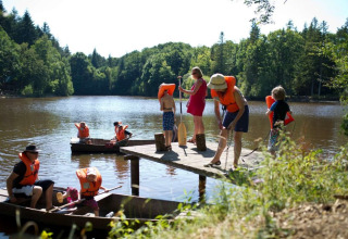 Familier ved en sø i Village Huttopia Senonches, Frankrig, nyder kano med redningsveste om sommeren.