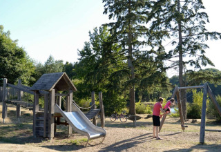 Legeplads med rutsjebane og gynger i natur omgivelser ved Village Huttopia Senonches i Frankrig.