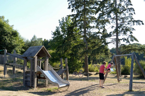 Spielplatz mit Rutsche und Schaukeln im Grünen im Ferienpark Village Huttopia Senonches, Frankreich.
