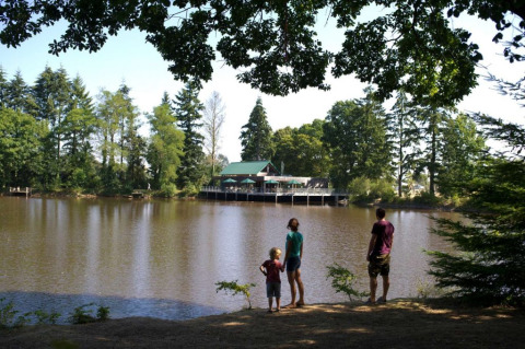 Familia contemplando el lago y los árboles en Village Huttopia Senonches, parque vacacional en Centre-Val de Loire, Francia.