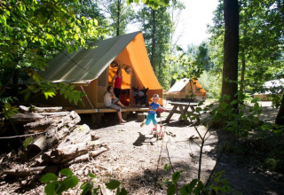 Familie nyder glamping i træhytter i en skovlysning på feriestedet Huttopia Senonches, Centre-Val de Loire.