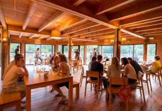 Vakantieparkrestaurant met houten interieur en gasten bij Village Huttopia Senonches, Centre-Val de Loire, Frankrijk.