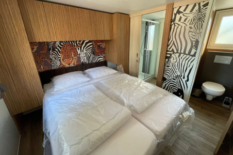 Dormitorio en SunLodge Babul, Camping Gasparina, Italia, con decoración de animales y baño privado.