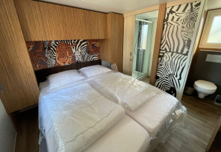Dormitorio en SunLodge Babul, Camping Gasparina, Italia, con decoración de animales y baño privado.