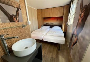 Chambre moderne au SunLodge Sabai en Italie avec lit double, décor animalier et lavabo intérieur.