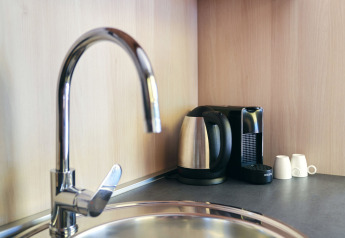 Kitchenette moderne avec bouilloire, machine à café, tasses et évier au SunLodge Sabai, Camping Gasparina.