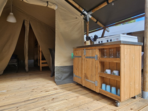 Innenansicht eines Safarizelts mit Holzboden, Küchenzeile und Essbereich im Camping Luna del Monte, Italien.