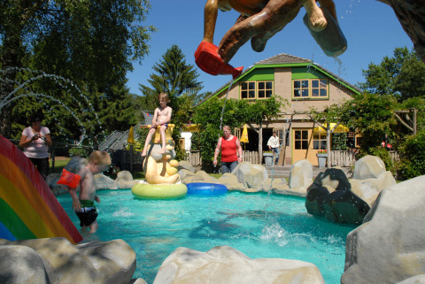 Niños juegan en una piscina infantil con estatuas coloridas en Veluwecamping 't Schinkel, Gelderland, Países Bajos.