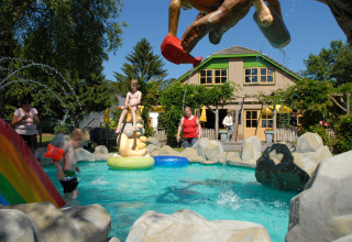 Niños juegan en una piscina infantil con estatuas coloridas en Veluwecamping 't Schinkel, Gelderland, Países Bajos.