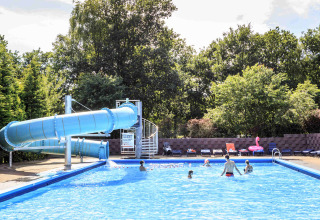 Outdoor swimming pool with large blue water slide and guests at Veluwecamping 't Schinkel in Gelderland, Netherlands.