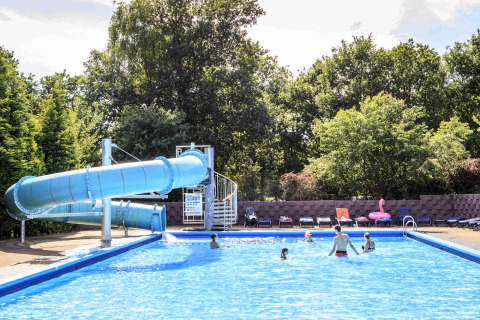 Buitenzwembad met grote blauwe glijbaan en bezoekers op Veluwecamping 't Schinkel in Gelderland, Nederland.