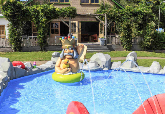 Outdoor children's pool with colorful statue and play area in front of a house at Veluwecamping 't Schinkel.