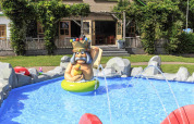 Outdoor children's pool with colorful statue and play area in front of a house at Veluwecamping 't Schinkel.