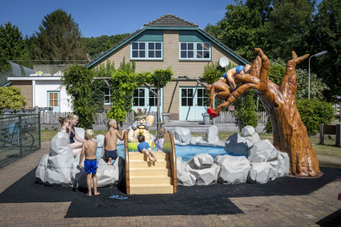 Children playing at a colorful water playground with figures and slide at Veluwecamping 't Schinkel, Netherlands.