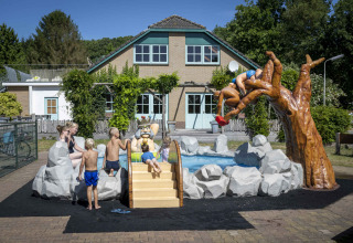 Children playing at a colorful water playground with figures and slide at Veluwecamping 't Schinkel, Netherlands.