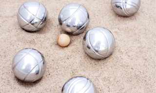 Bolas de petanca y bola objetivo en la arena, juego típico en parques de vacaciones con glamping.