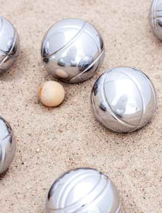 Bolas de petanca y bola objetivo en la arena, juego típico en parques de vacaciones con glamping.