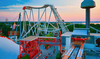 Parque de atracciones con montaña rusa y torre al atardecer cerca de Castelnuovo del Garda, Véneto, Italia.