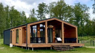 Moderna cabaña The Beach House en Wilsumer Berge, Alemania, rodeada de césped y árboles verdes.