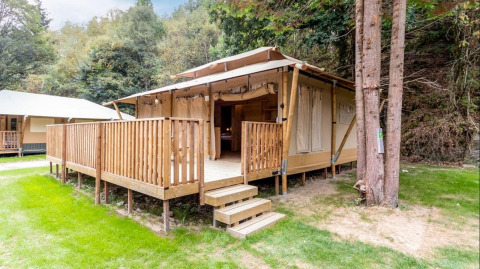 Safari teltet Stardust 40 Family Lodge på Petite Suisse i Belgien omgivet af grønne træer og natur.