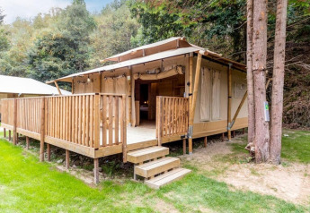 Stardust 40 Family Lodge safari tent at Petite Suisse, Belgium, with wooden deck and forest backdrop.