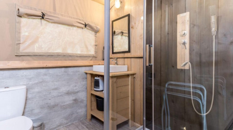 Baño de una tienda safari Stardust 40 Family Lodge con ducha, lavabo, madera y ventana en Bélgica.