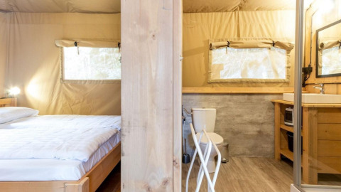 Interior de tienda safari Stardust 40 Family Lodge con dormitorio y baño, Petite Suisse, Bélgica.