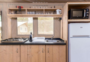 Kitchen area of a safari tent at Stardust 40 Family Lodge, Petite Suisse, Belgium, with stove, fridge and microwave.