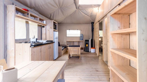 Tienda safari Stardust 40 Family Lodge en Petite Suisse, Bélgica, con interior de madera y cocina equipada.