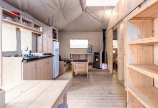 Tienda safari Stardust 40 Family Lodge en Petite Suisse, Bélgica, con interior de madera y cocina equipada.