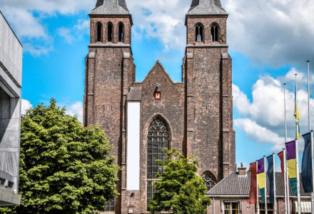 Iglesia de torres gemelas y fuente delante, foto tomada en Hoenderloo, Güeldres, Países Bajos.