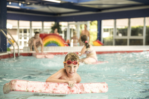 Et barn i svømmehal leger med svømmebræt i Holiday Park Mölke, en feriepark i Overijssel, Holland.