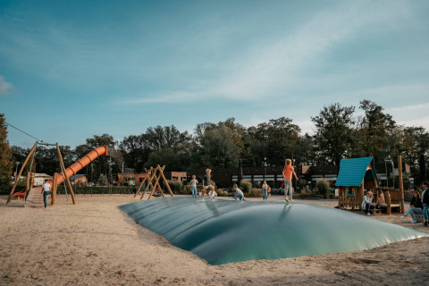 Niños juegan y saltan sobre un cojín hinchable en el parque infantil de Camping de Italiaanse Meren, Gelderland.