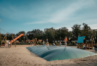 Niños juegan y saltan sobre un cojín hinchable en el parque infantil de Camping de Italiaanse Meren, Gelderland.