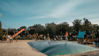 Niños juegan y saltan sobre un cojín hinchable en el parque infantil de Camping de Italiaanse Meren, Gelderland.