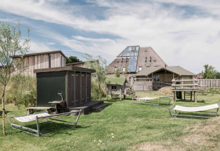 Uitzicht op Duynpark Het Zwanenwater vakantiepark met ligbedden, houten hutten en modern gebouw in Noord-Holland.