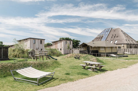 Holiday park Duynpark Het Zwanenwater in North Holland, Netherlands, with cabins, hammocks, and picnic tables.