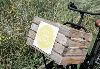 Fahrrad mit Holzkiste und dem Schild 'zon zee strand' im Ferienpark Duynpark Het Zwanenwater, Niederlande.