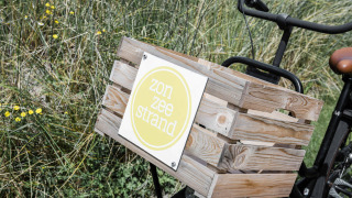 Fahrrad mit Holzkiste und dem Schild 'zon zee strand' im Ferienpark Duynpark Het Zwanenwater, Niederlande.