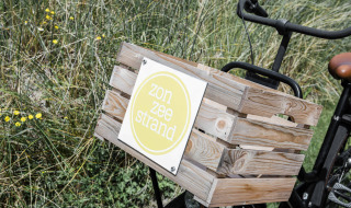 Bicycle with wooden crate and 'zon zee strand' sign at Duynpark Het Zwanenwater holiday park, North-Holland.