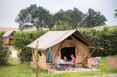 Famiglia che campeggia fuori da una tenda a Huttopia Pays de Cordes sur Ciel in Occitania, Francia.