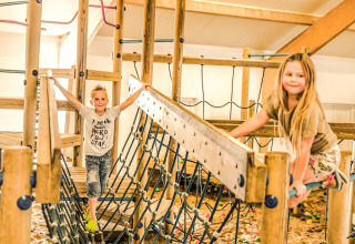 To børn leger på en indendørs legeplads med klatrestativer i Holiday Park Mölke, Overijssel, Holland.
