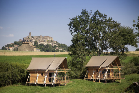 Dos cabañas en un campo verde con vistas al pueblo medieval de Cordes-sur-Ciel en Occitania, Francia.